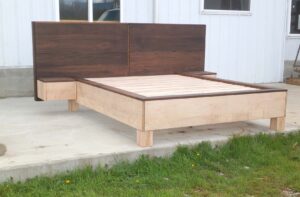 side view of a platform bed with large headboard and attached side tables