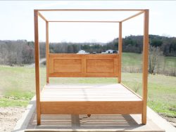front view of wood canopy bed with headboard